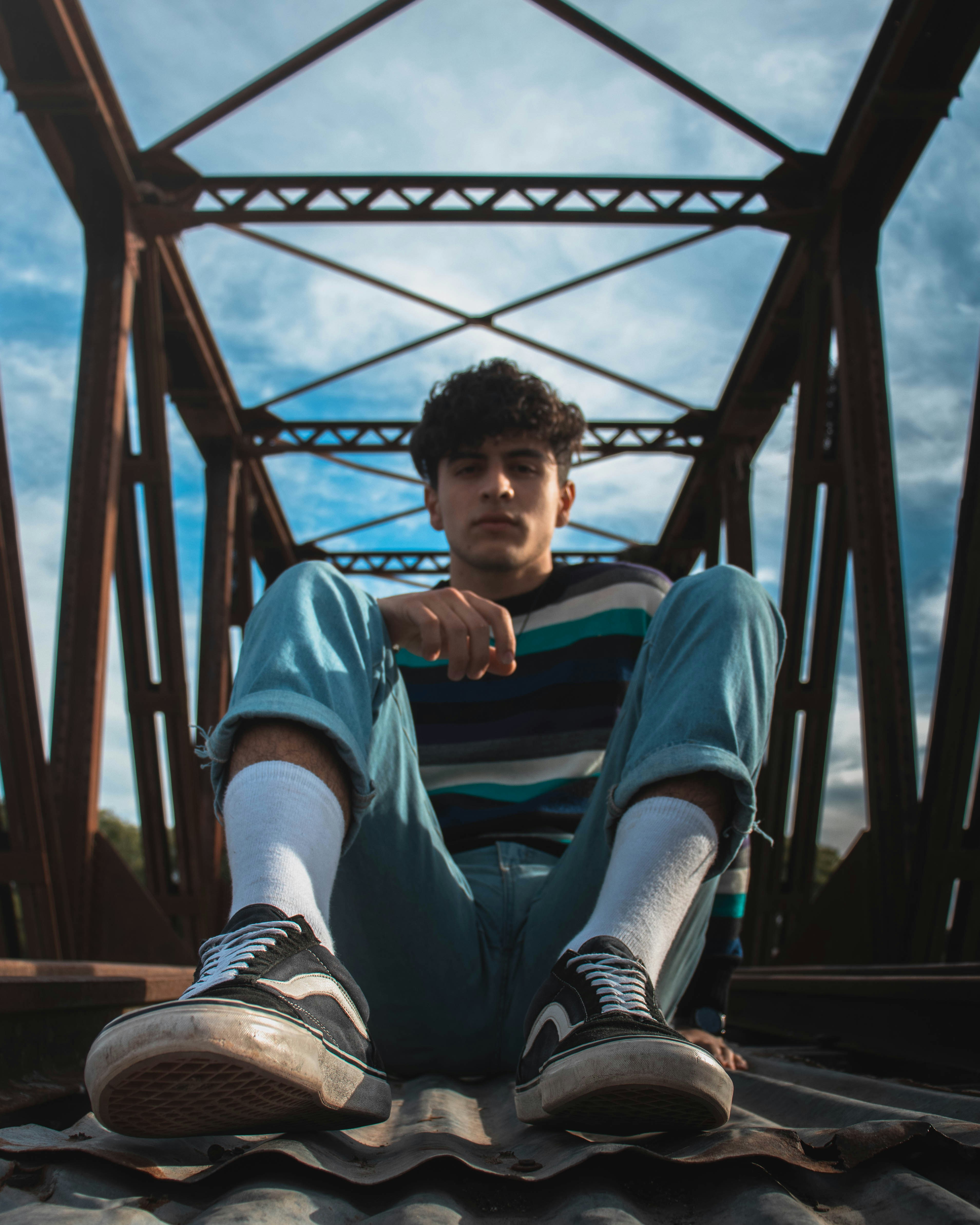 man in blue jacket and blue denim jeans sitting on brown wooden dock during daytime
