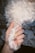 A hand with colorful, artistic nail art holds a fluffy white dog's paw. The nails feature intricate designs, such as stripes and swirls. The dog's fur is curly and white, and it contrasts with the painted nails.