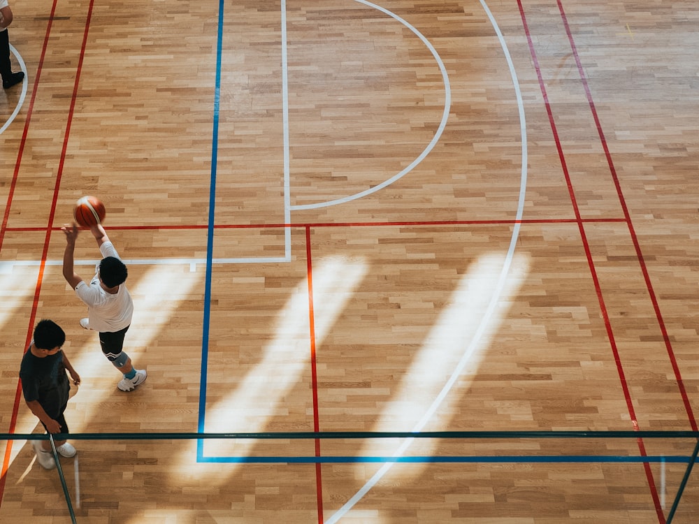 Hombre con camisa blanca y pantalones negros jugando al baloncesto