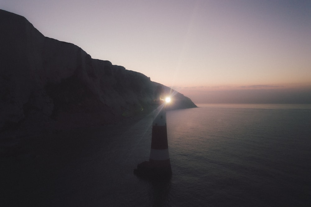 silhouette of person standing on rock formation during sunset