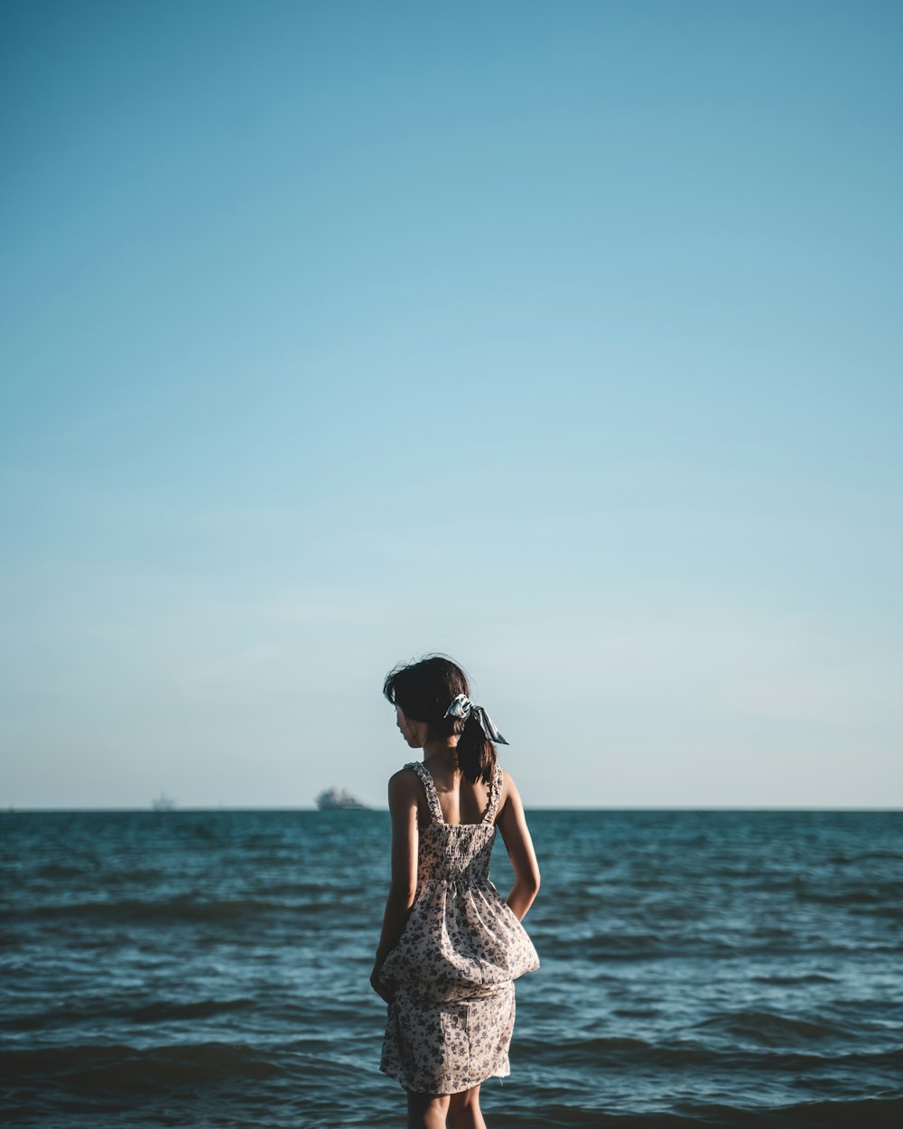 woman in white and black dress standing on beach during daytime