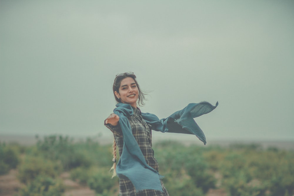 woman in blue denim jacket and blue denim jeans standing on field with flying bird