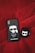 A black phone case and a black earbud case with cartoon illustrations are placed on a red textured surface. The phone case features a cartoon character with sunglasses and a white ponytail with the name 'Karl Lagerfeld' inscribed beneath. The earbud case has a cartoon cat wearing sunglasses.