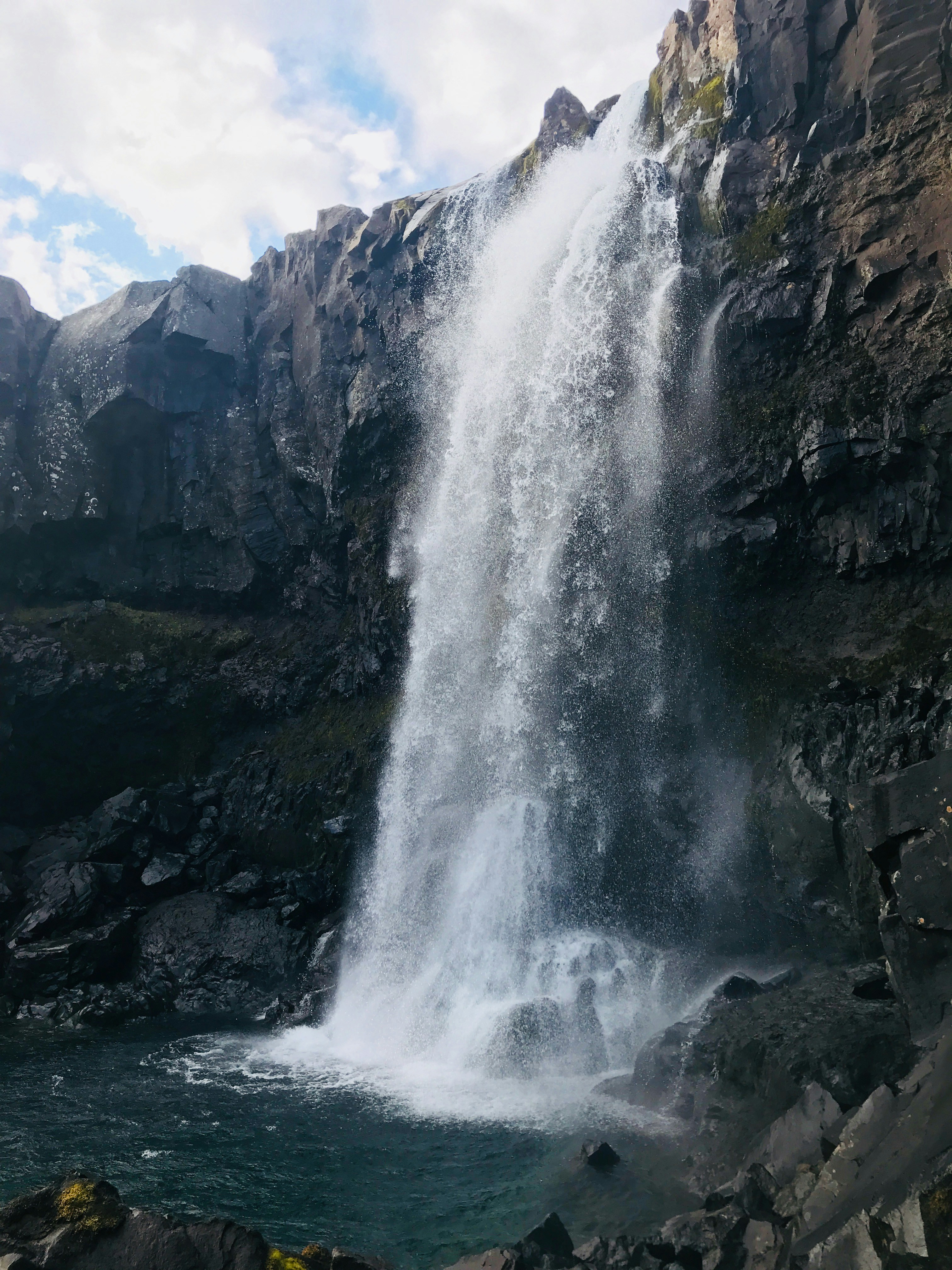 water falls on rocky mountain during daytime