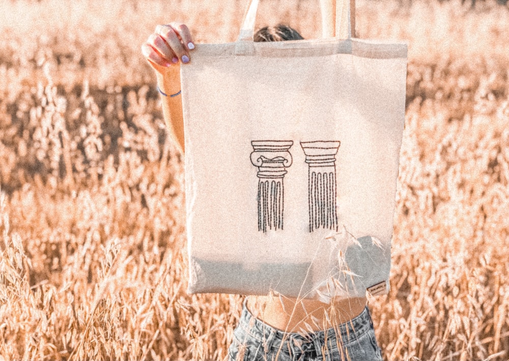 woman in white and black striped shirt holding white tote bag