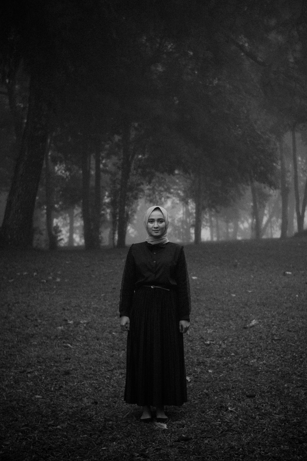 woman in black dress standing on grass field in grayscale photography