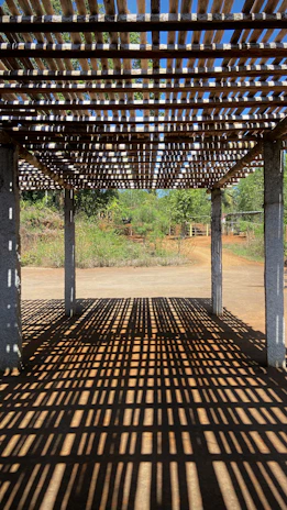 A stylish pergola casting soft shadows over a cozy outdoor seating area surrounded by greenery.