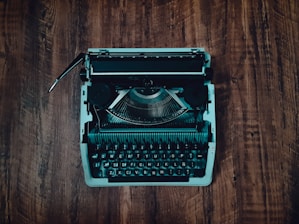 green and black typewriter on brown wooden table