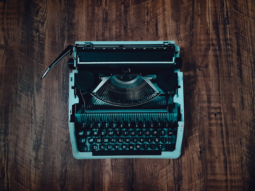 green and black typewriter on brown wooden table