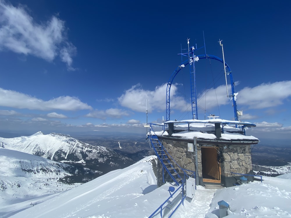 Braunes Holzhaus auf schneebedecktem Berg unter blauem Himmel tagsüber
