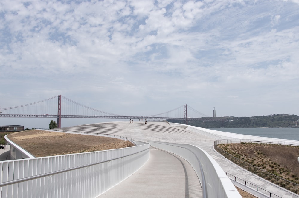 gray concrete road near bridge under white clouds during daytime