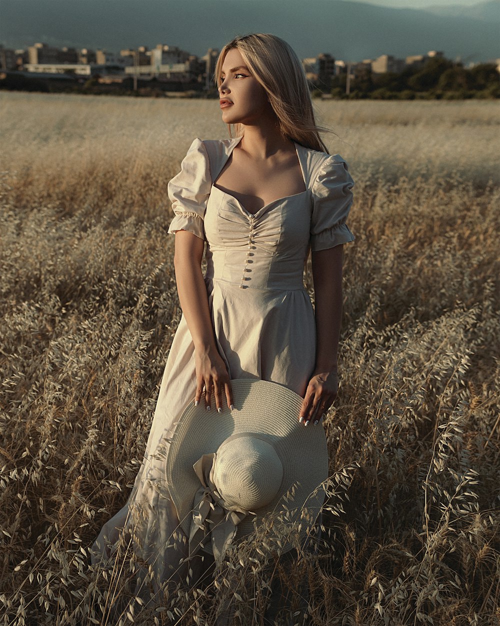 woman in white dress sitting on brown grass field during daytime