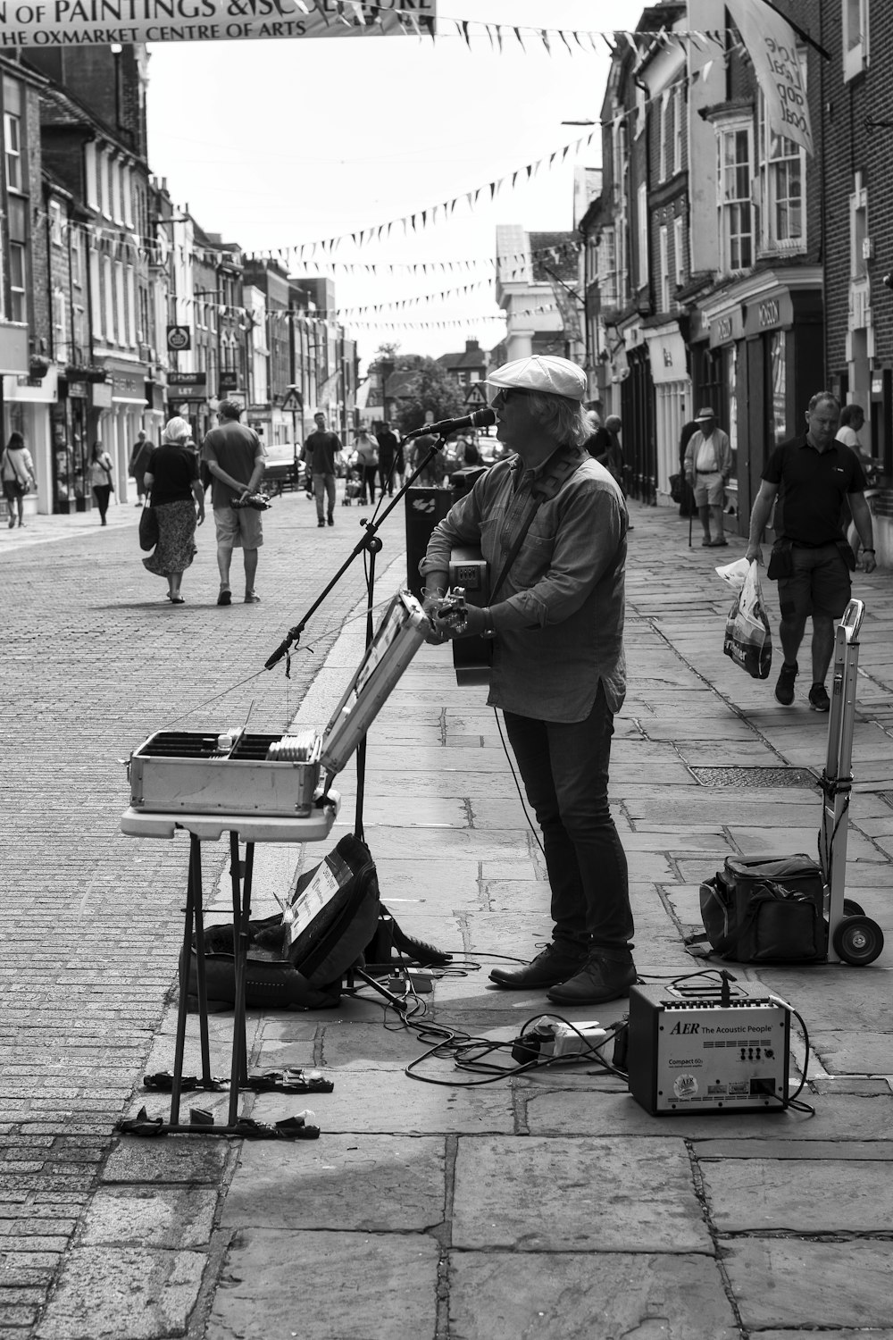man playing guitar on street in grayscale photography