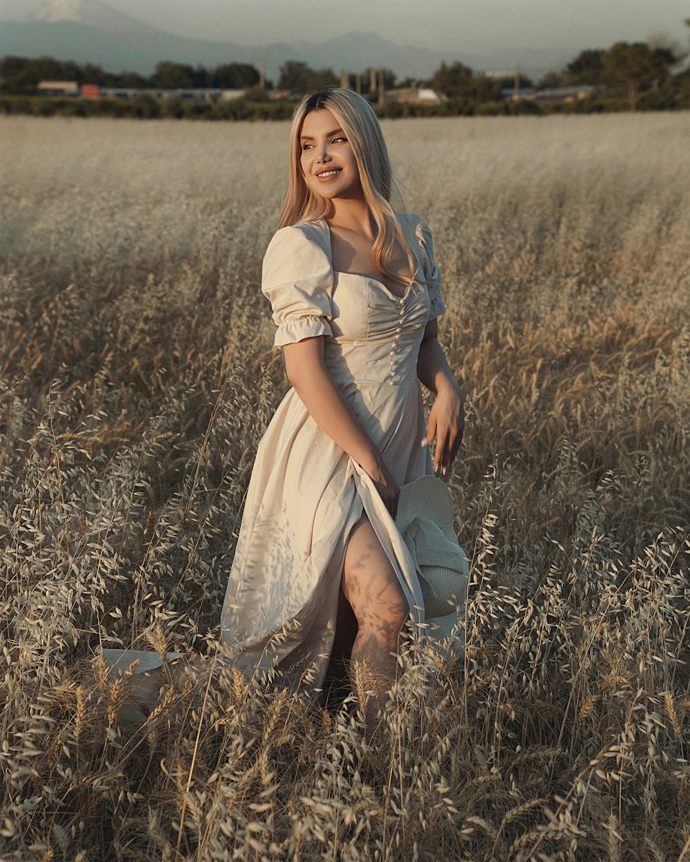 Mujer en vestido blanco de pie en el campo de hierba marrón durante el día