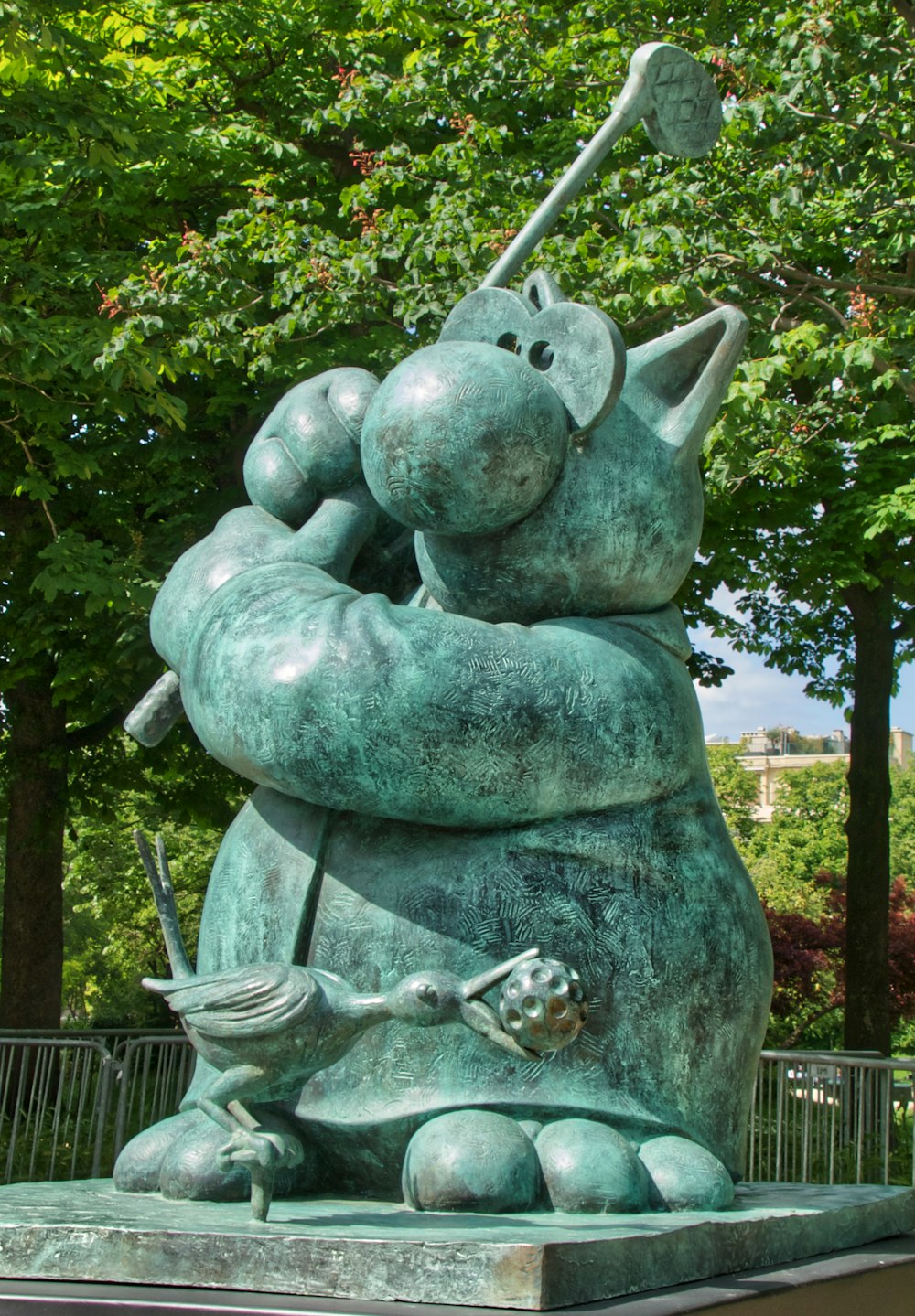 gray concrete statue with green plants in the background during daytime