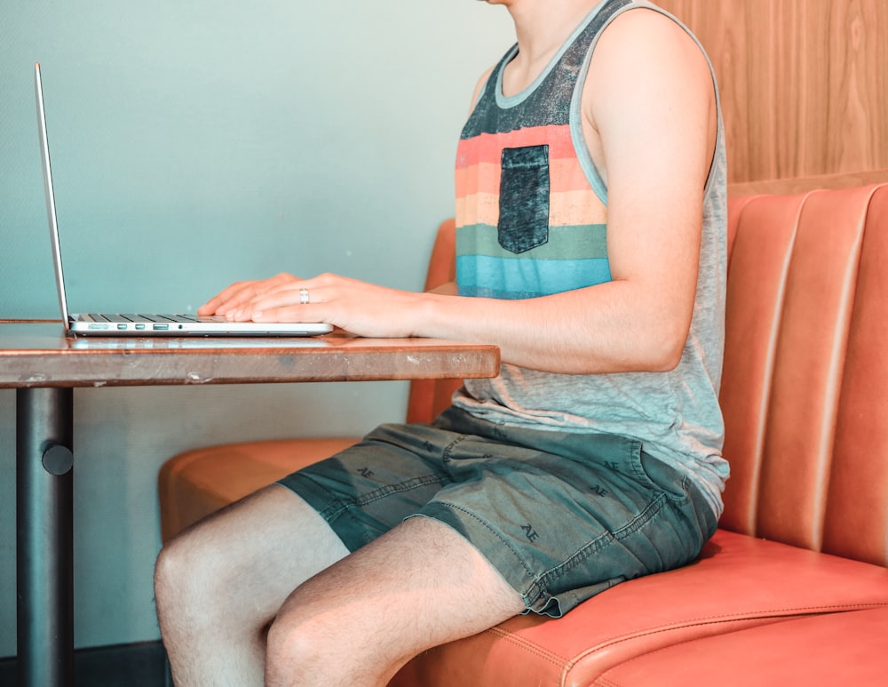 woman in blue and red tank top and blue denim shorts sitting on brown wooden chair