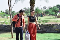 Man and woman dressed in chic, minimalist outfits walking through a city park.