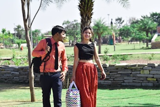 A smiling man and woman walking together in a park on a sunny day.