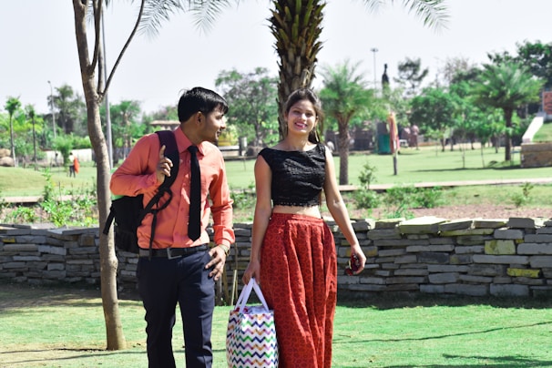 A stylish man and woman sharing a laugh during a sunset walk in the park.