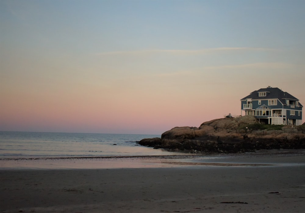 white and brown house on brown rock formation by the sea during daytime