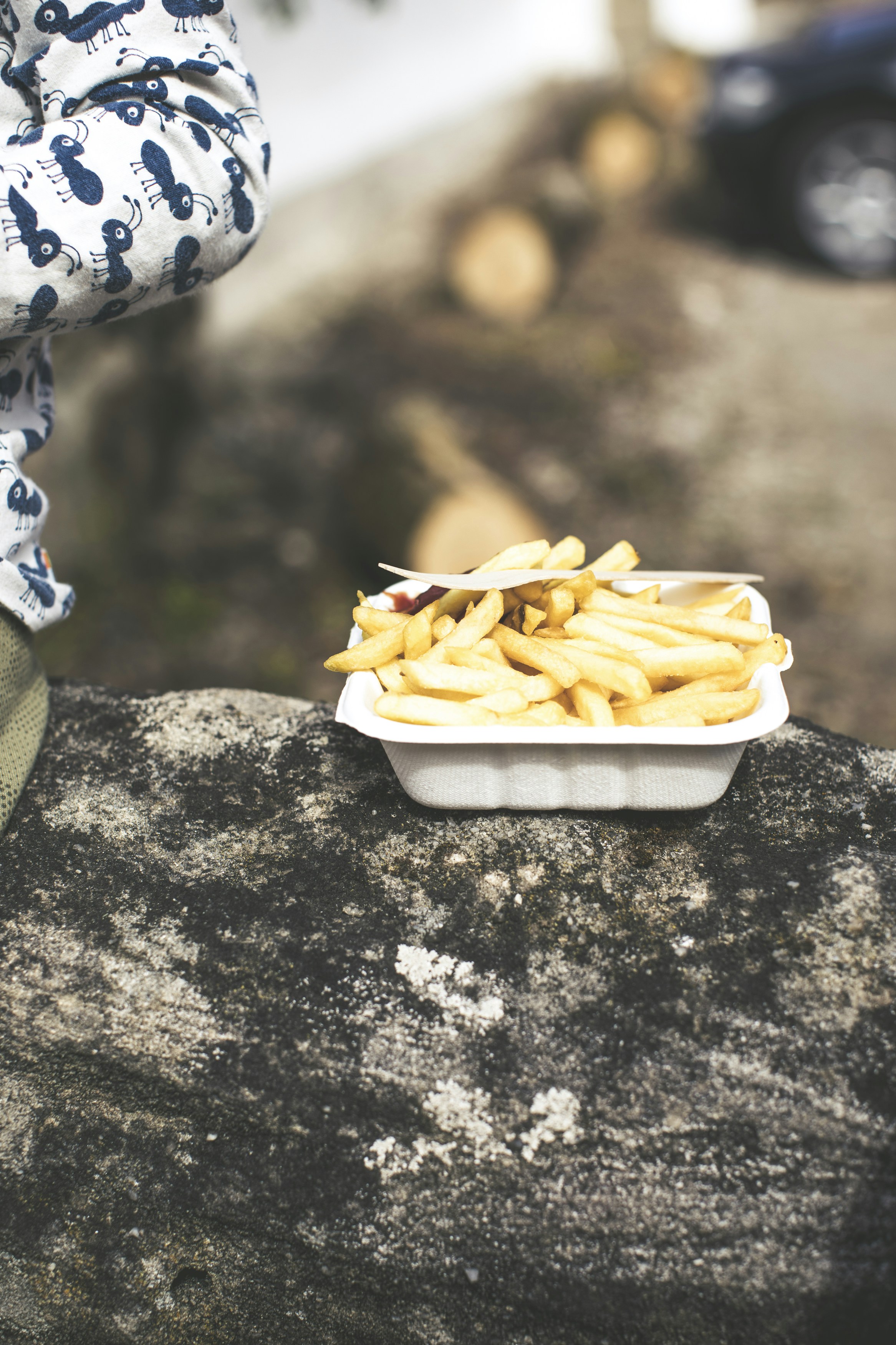 A young boy happily eating a large plate of french fries.
