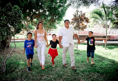 Children happily walking in a park holding hands with caregivers under sunny skies.