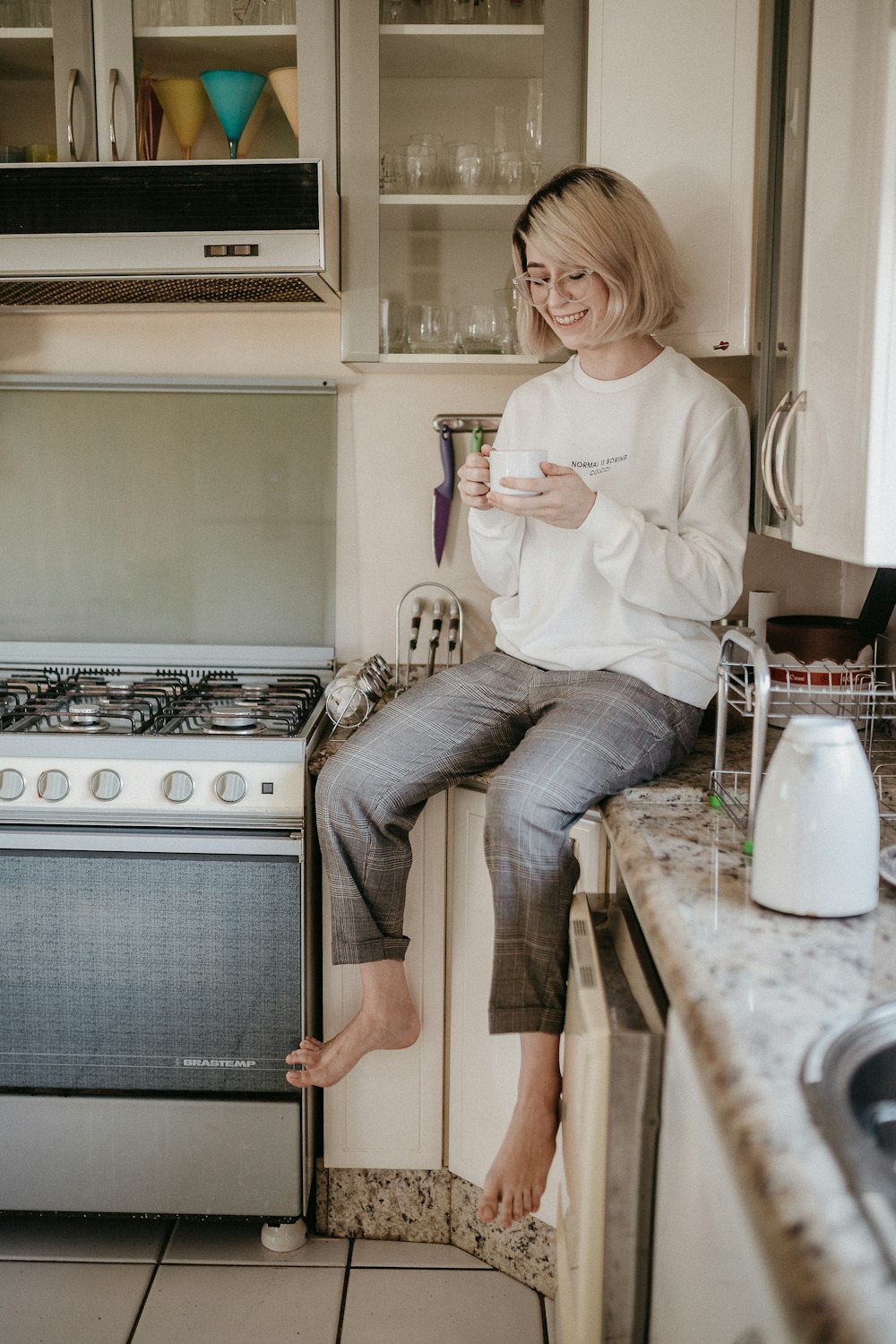 woman in white long sleeve shirt and blue denim jeans sitting on brown wooden table