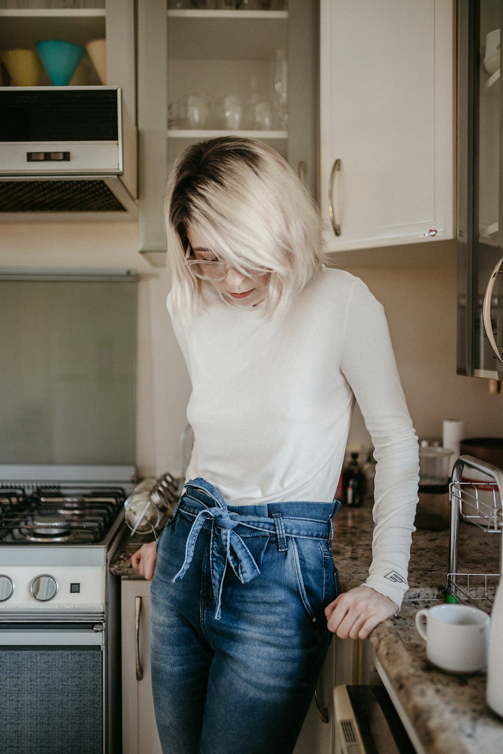 woman in white long sleeve shirt and blue denim shorts standing in kitchen