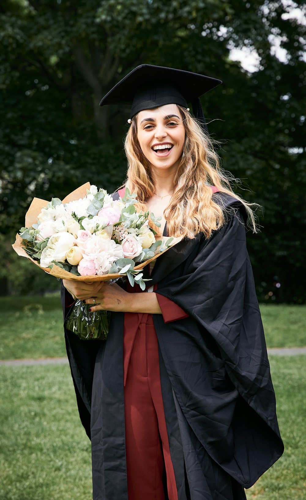 woman in black academic dress holding bouquet of flowers