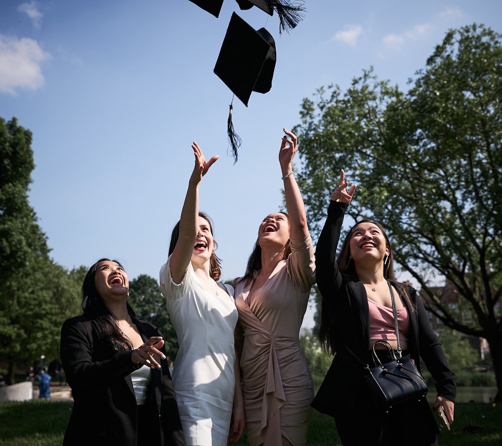 3 women smiling and standing under blue sky during daytime