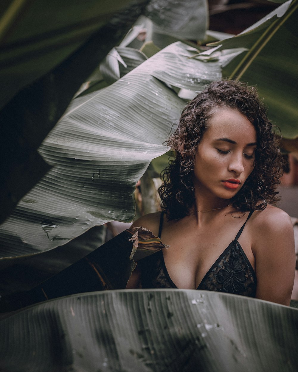 woman in white spaghetti strap top standing beside green banana plant