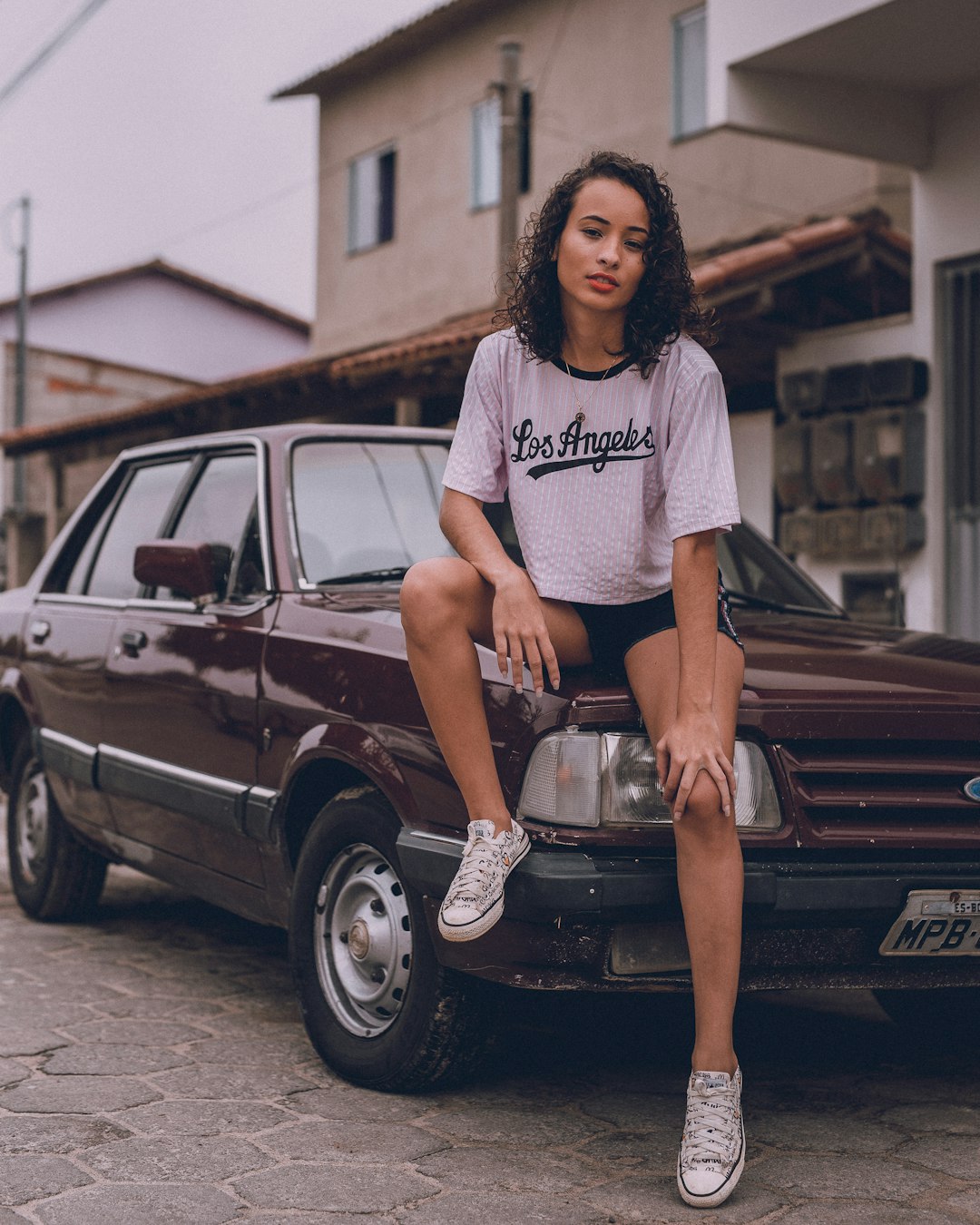 woman in white and black crew neck t-shirt and black skirt standing beside black car