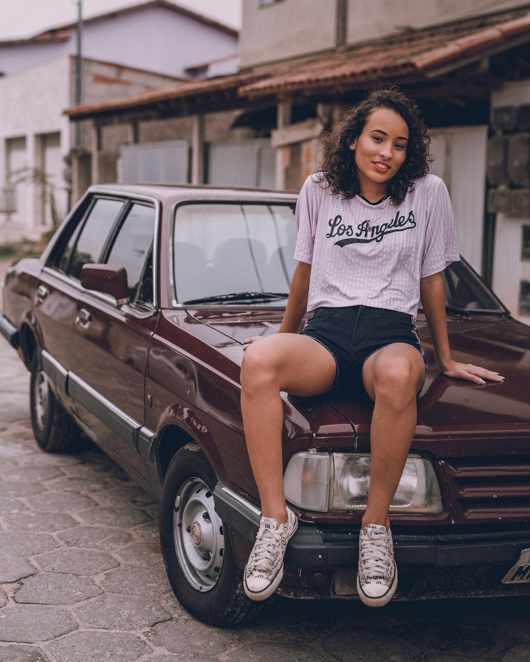 woman in white and black crew neck t-shirt sitting on brown car