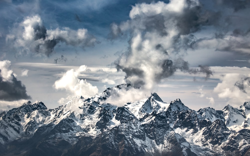 snow covered mountain under white clouds during daytime