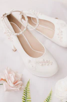 Elegant bridal shoes with subtle gold accents resting on creamy white lace.