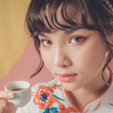 girl in white and red floral shirt holding white ceramic mug