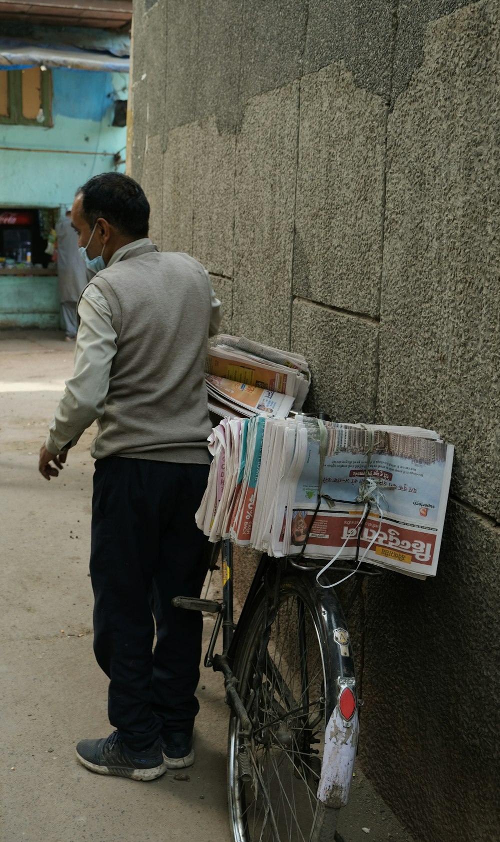 man in gray sweater and black pants standing beside bicycle