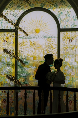 A couple holding hands in prayer, sunlight streaming through a church window behind them