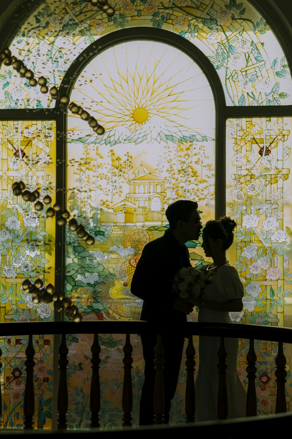man and woman kissing under yellow floral arch