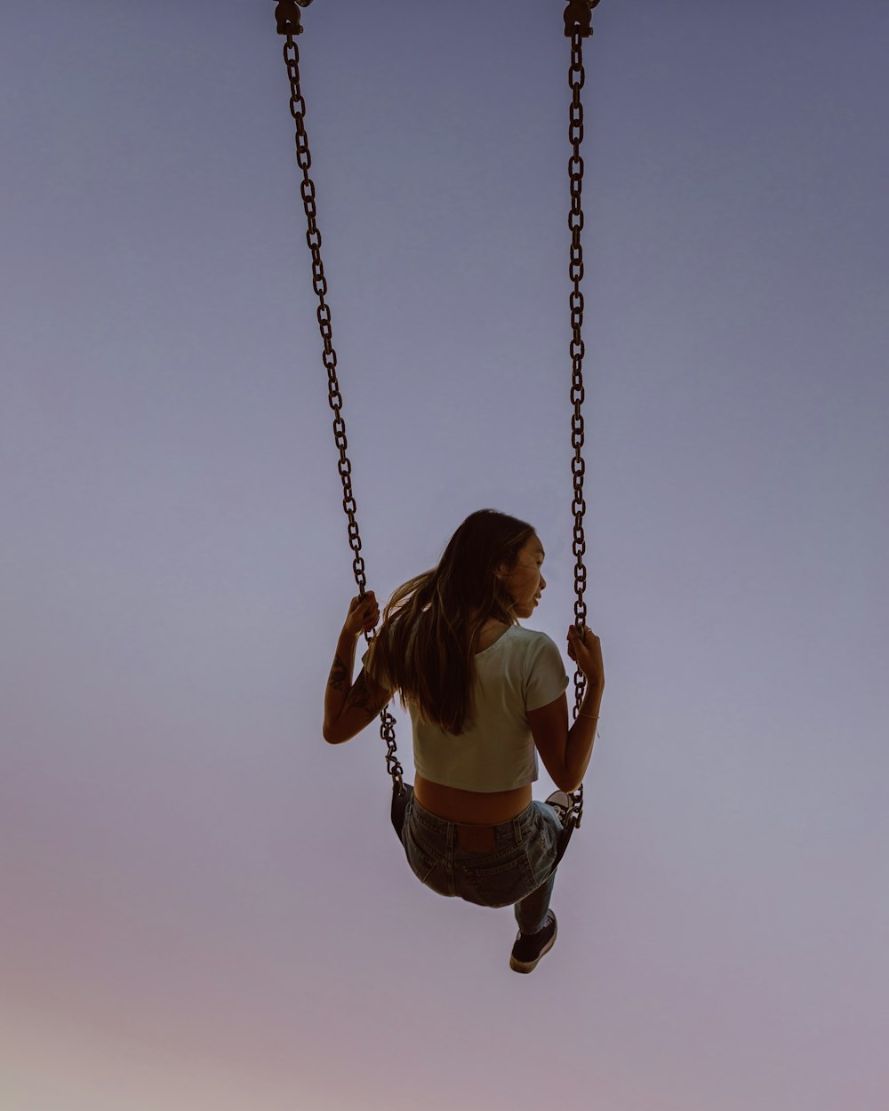 girl in white tank top sitting on swing during daytime