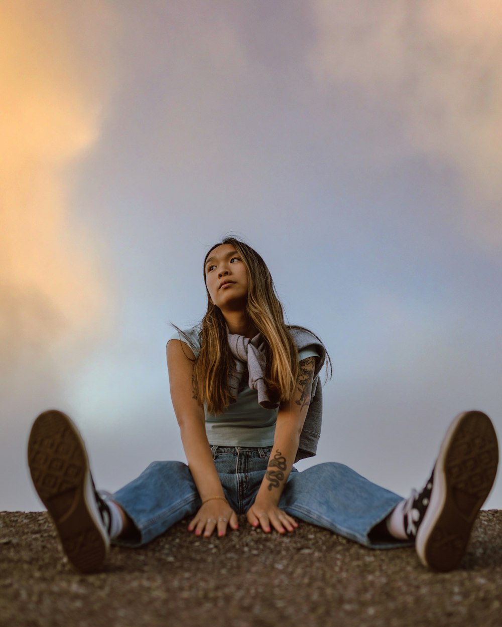 woman in black shirt and blue denim jeans sitting on brown rock