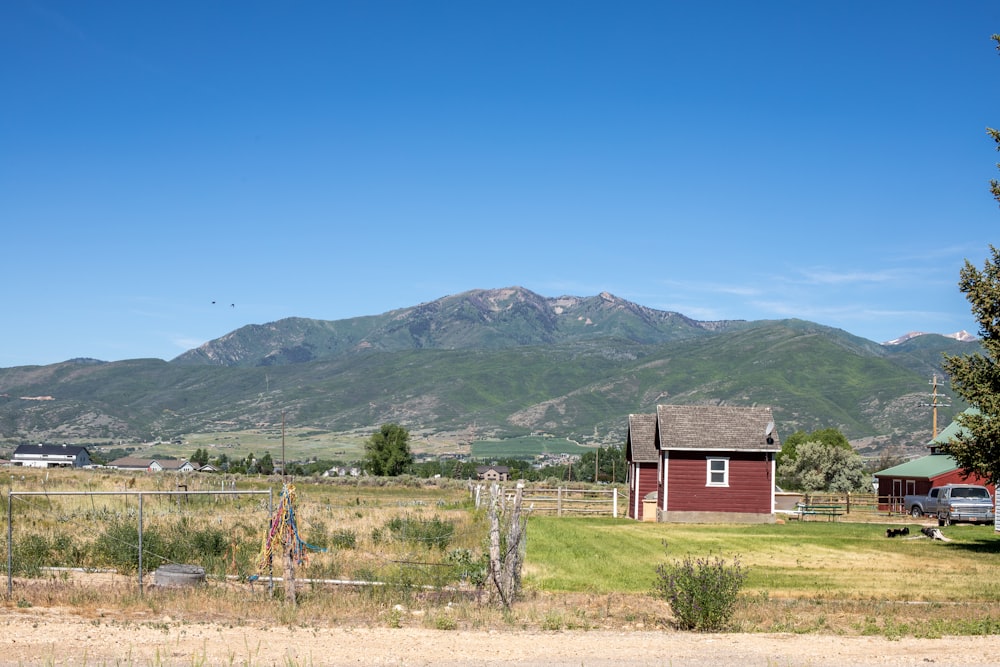 red and white barn near green mountain under blue sky during daytime