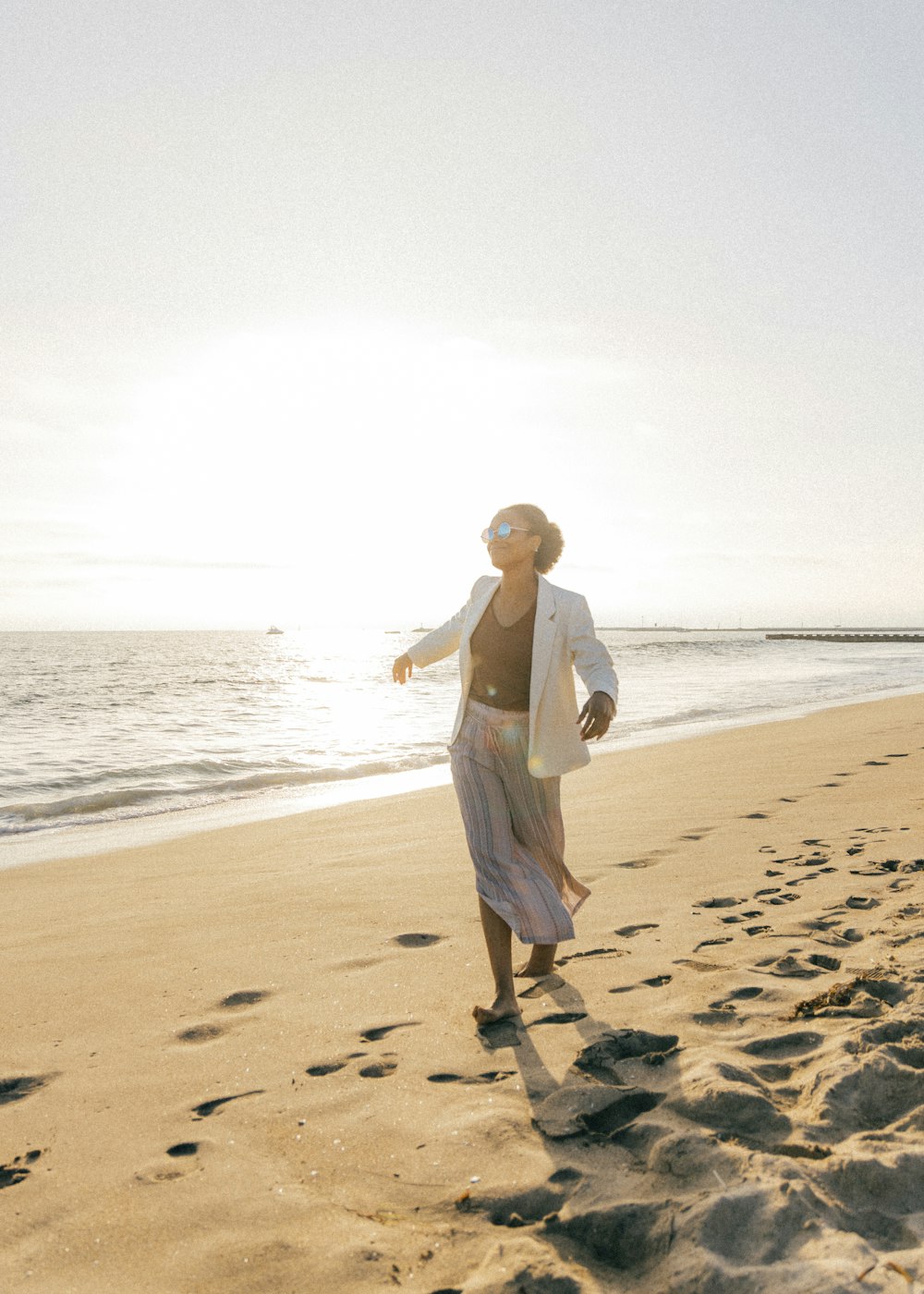 낮 동안 해변에 서 있는 하얀 드레스를 입은 여자