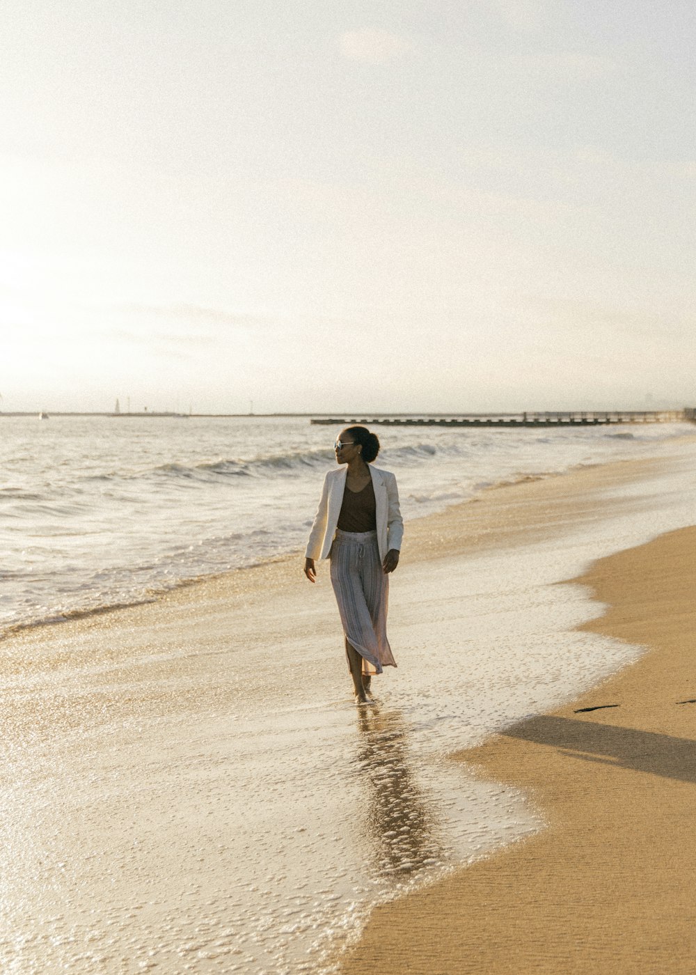 donna in vestito bianco che cammina sulla spiaggia durante il giorno