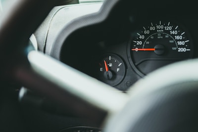 A close-up of a fuel gauge showing low levels in a car dashboard.