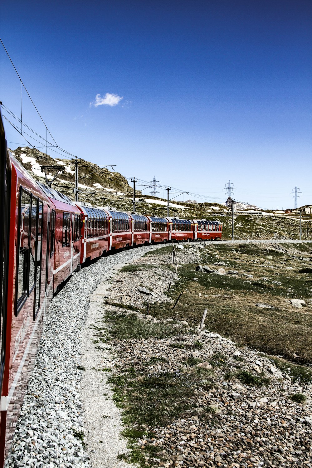 red and white train on rail tracks under blue sky during daytime