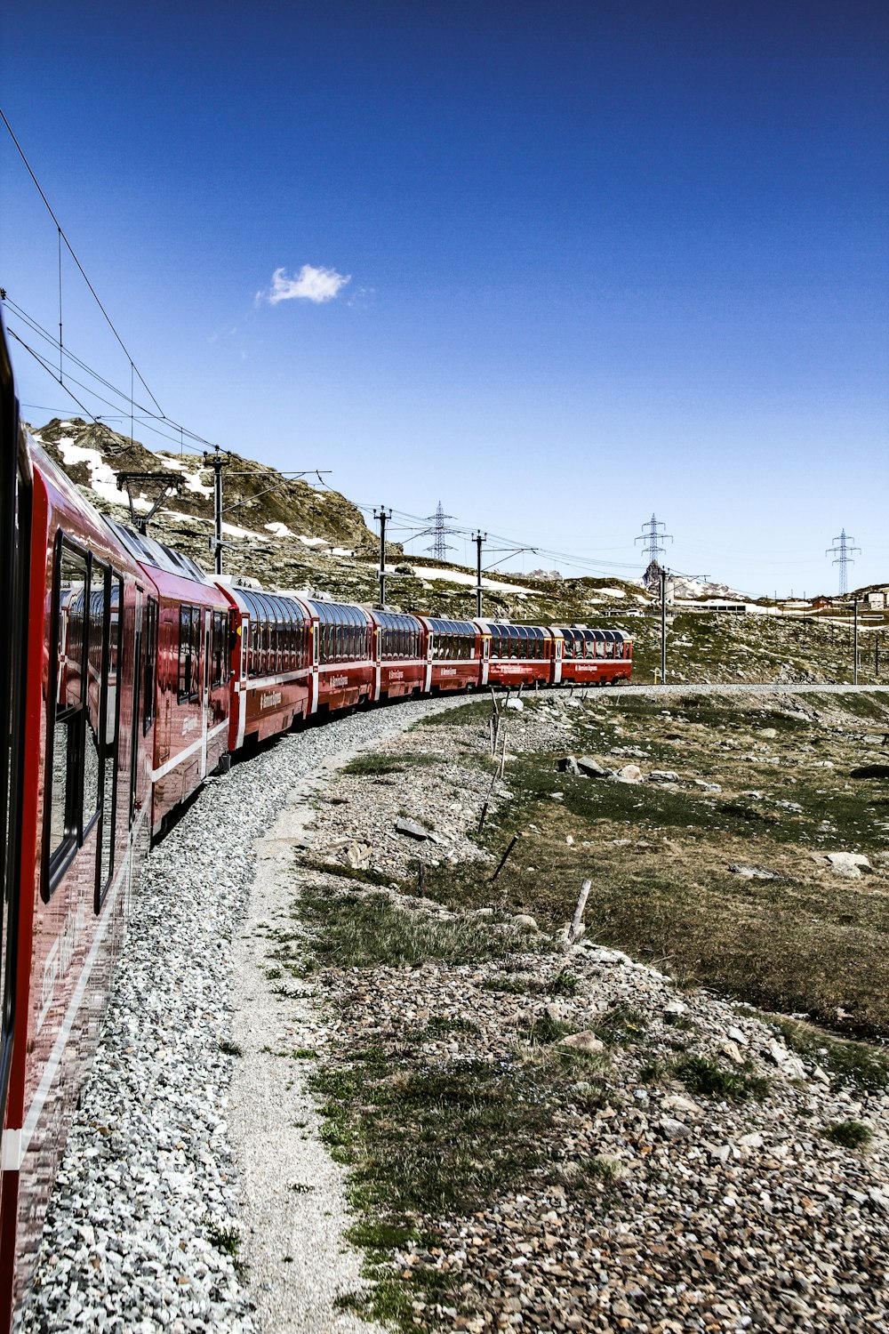 rot-weißer Zug tagsüber auf Bahngleisen unter blauem Himmel