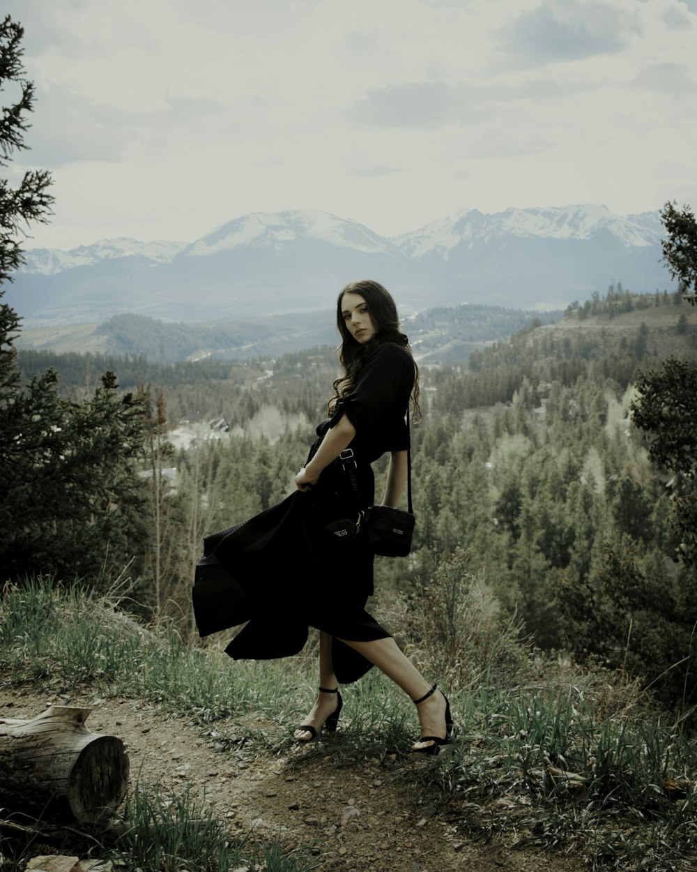 woman in black dress sitting on brown rock during daytime