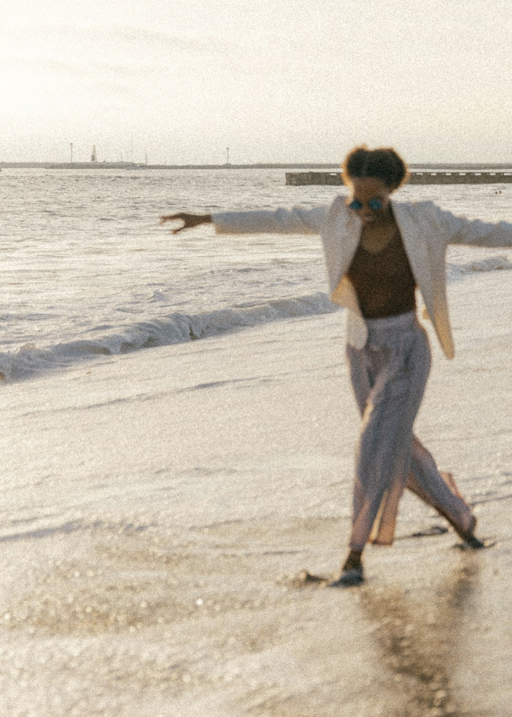woman in gray pants walking on white sand during daytime