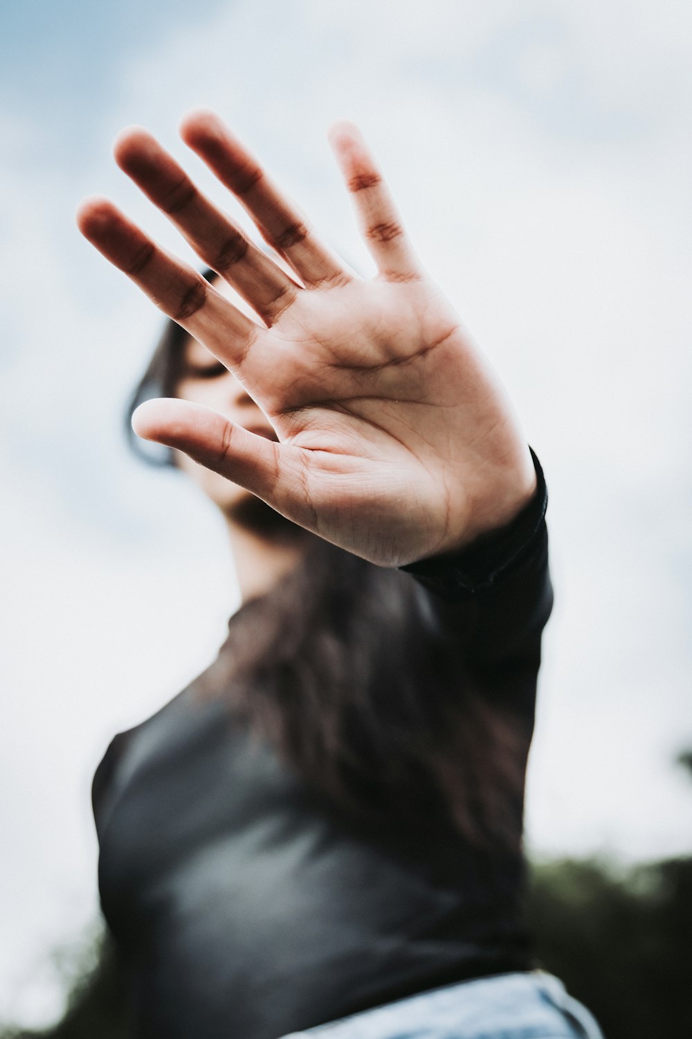 woman in gray long sleeve shirt covering her face with her hand